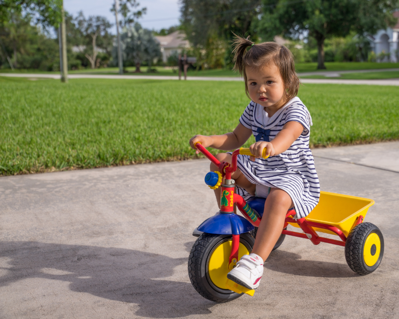 photo of young child riding tricycle