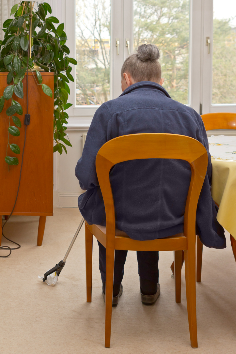 photo of person sitting and using a long handled reacher