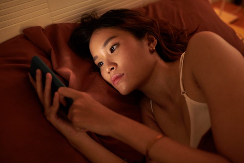 photo of female holding handheld device in bed